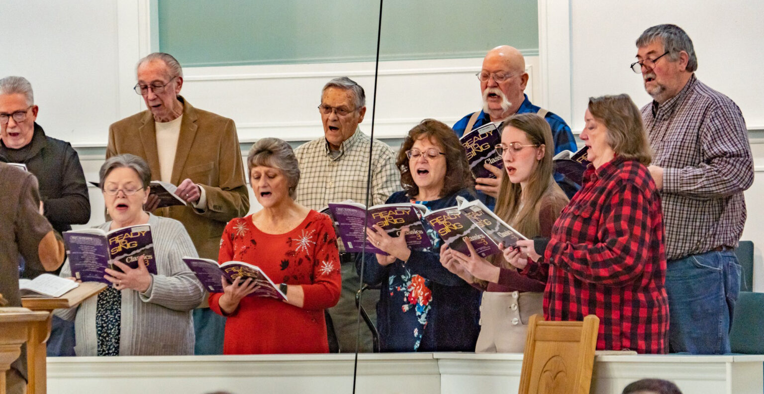 The Riverside Choir standing and singing in the choir loft