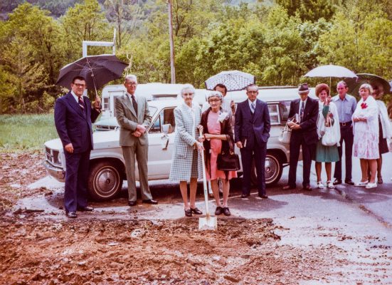 Church members stand in the parking lot, participating in a groundbreaking ceremony.
