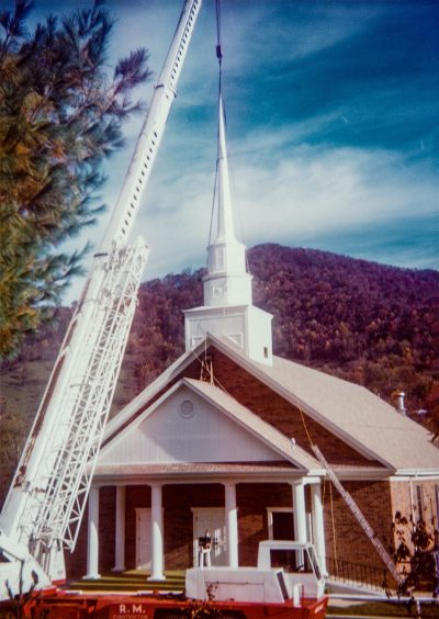 The steeple is installed on the roof of the church building.